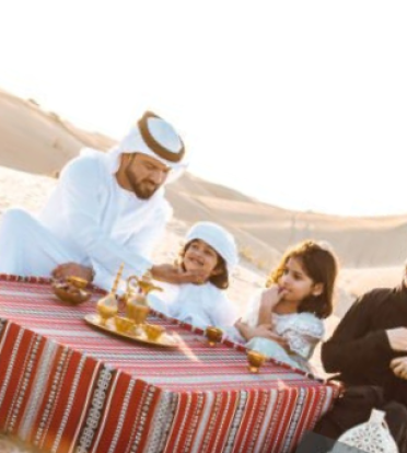A Group Of People Sitting On A Blanket In A Desert